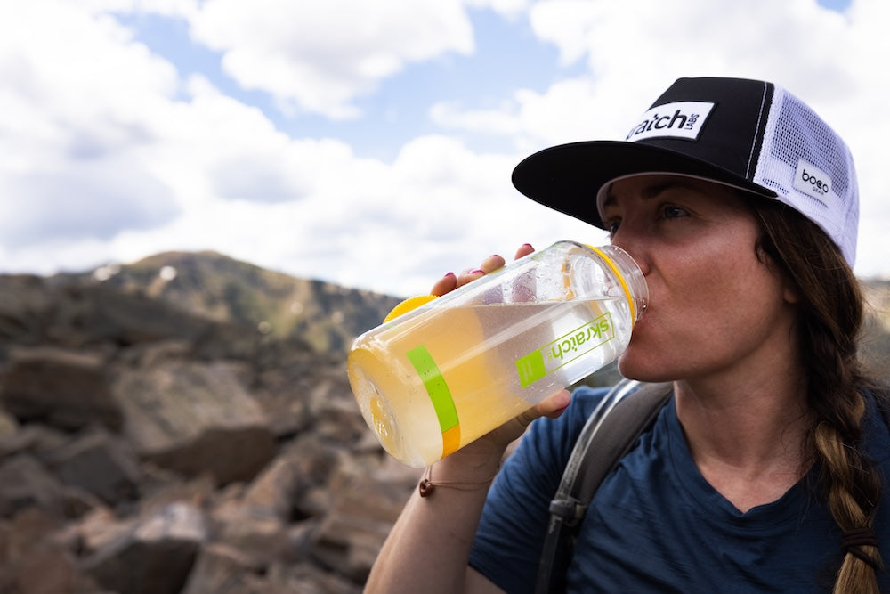 Skratch Labs Hydration Everyday Drink Mix packets in a vibrant outdoor setting, showcasing the product's packaging design.